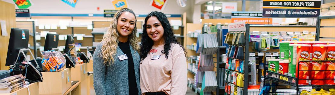 两名学生工作者微笑地站在皮马书店里